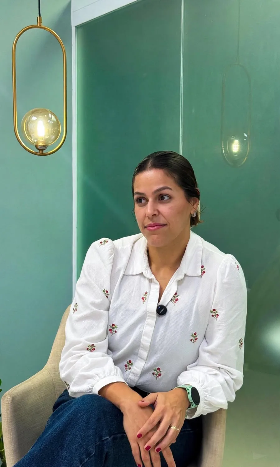 Ambiente do consultório com paredes verde-água e luminária dourada